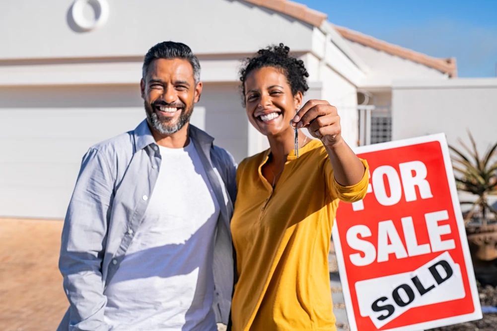 Couple holding keys standing in front of their new home